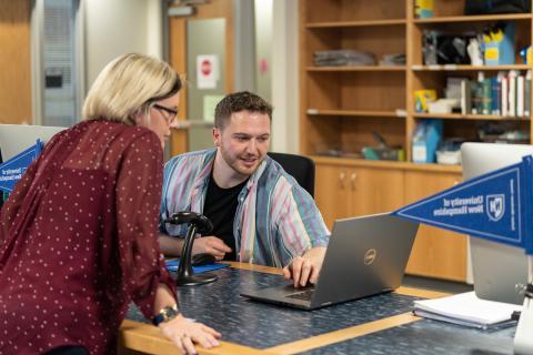 Two people looking at computer in library